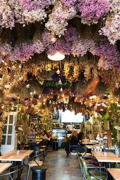 the interior of a flower shop with lots of flowers hanging from the ceiling