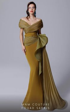 In this MNM COUTURE 2692 creation, ascend to a whole new level of sophistication. This gown has fine pleats on panels that wrap into a surplice design. Structured with an off shoulder neckline on a corset defined bodice and nipped with a tonal belt, the waist is graced with a voluminous ruffle at one side. Pleats drape the skirt, forming a mermaid silhouette with a cascading sash and a sweeping train. Make your presence known in this MNM COUTURE masterpiece. Models are wearing the Fuchsia, Olive Olive Gown, Plus Size Gowns Wedding, Fouad Sarkis, Mnm Couture, Off Shoulder Gown, Mermaid Evening Gown, Plus Size Gowns, Gown Plus Size, Festa Party