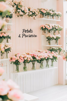 a flower shop with pink and white flowers on the wall, along with shelves filled with roses