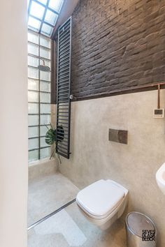 a white toilet sitting next to a window in a bathroom under a slanted skylight