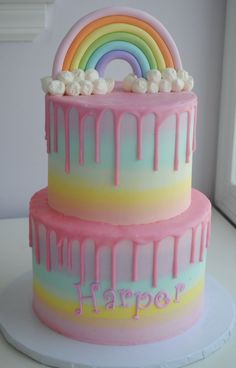 a three layer cake with rainbow icing and marshmallows on the top