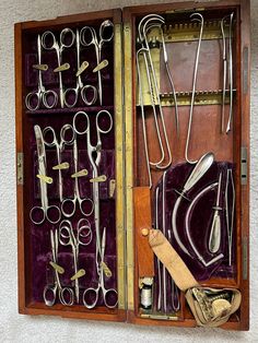 an open wooden box with many pairs of scissors and other items in it on display