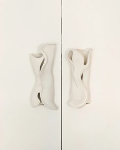 two white vases sitting next to each other in front of a wall mounted mirror