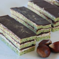 three pieces of cake sitting on top of a white plate next to nuts and chocolate