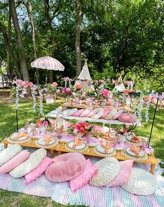 a table with plates and umbrellas on it in the middle of a park area