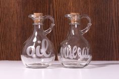 two glass jugs with the words oil and vinegar painted on them sitting side by side