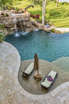 an outdoor pool with lounge chairs and waterfall