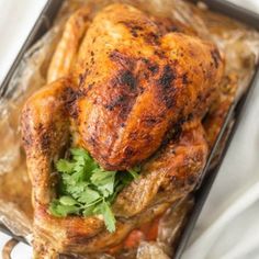 a roasted chicken with parsley in a roasting pan on a white tablecloth