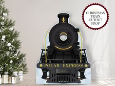 a black and gold train engine next to a christmas tree with the words polar express on it