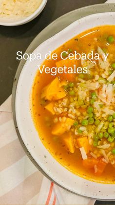 a bowl of soup with peas, carrots and rice