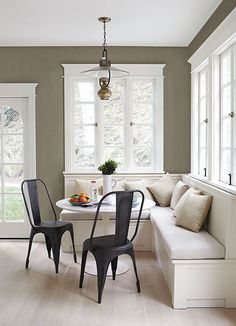 a room with white walls and wooden floors, two black chairs in front of the table