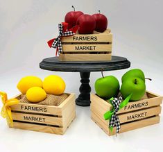 three wooden crates with apples, oranges and pears in them on a table