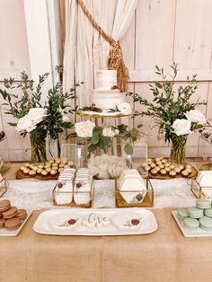 a table topped with cakes and desserts next to tall vases filled with flowers