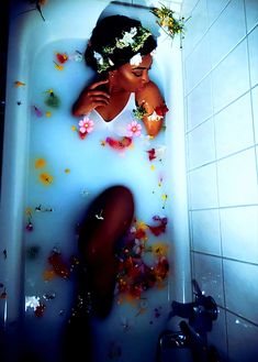 a woman sitting in a bathtub with flowers all over her body and head, surrounded by petals