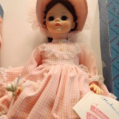 the doll is wearing a pink dress and hat