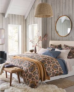 a bedroom with wood paneling and a bed covered in blue and brown sheets, pillows and blankets