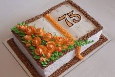 a decorated cake with an orange ribbon and number 75 on it's side sitting on a table