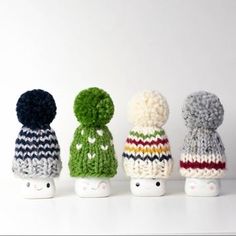 four small knitted toys are lined up in the same row and one is wearing a hat