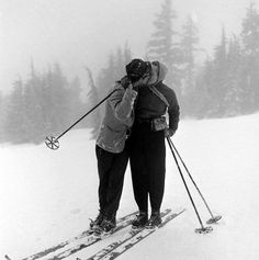 two people standing on skis in the snow with their backs turned to each other