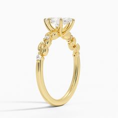 a yellow gold engagement ring with a pear shaped diamond on the center and side stones