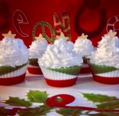 cupcakes decorated with white frosting and holly leaves are on a platter