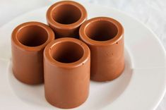 four chocolate cups sitting on top of a white plate