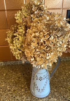 a blue vase filled with lots of flowers on top of a counter