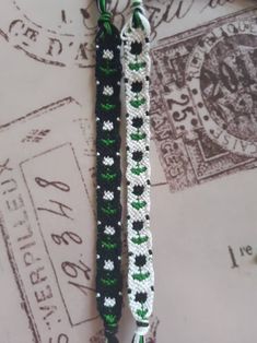 two black and white crocheted bracelets on top of a postage stamp with green accents