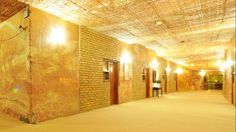 an empty hallway with brick walls and lights on either side of the door, leading to another room