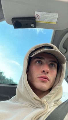 a man wearing a hoodie sitting in the back seat of a car