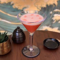 a drink sitting on top of a wooden table next to a potted plant