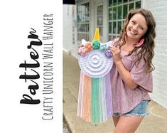 a woman is holding up a crocheted unicorn bag with a rainbow horn on it