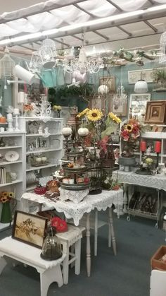 a room filled with lots of white tables and chairs next to shelves full of vases