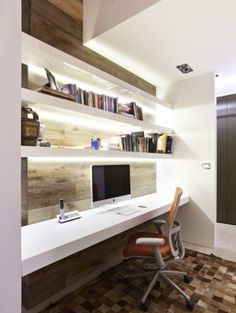 a computer desk with a monitor on top of it next to a bookshelf