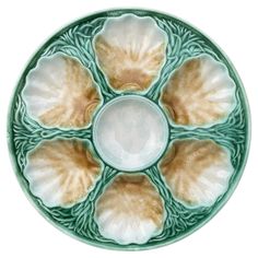 a green and white plate with four seashells on it's center piece