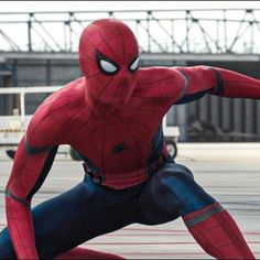 the spider - man is posing in front of an empty parking lot with his arms spread out