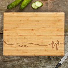 a cutting board with cucumbers on it next to a knife and pickles