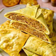 three burritos stacked on top of each other on a white plate with green garnishes