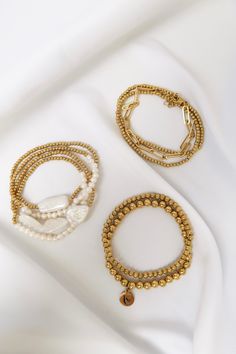 Looking for a stunning and unique accessory? Look no further than the Noho Pearl Shell 9 Piece Stack. This luxurious Gold bracelet stack features 2 matching dainty bracelets accompanied by 22 mini pearl shell beads, 4 matching dainty Gold bracelets, 1 adjustable up to 9 inches paperclip style bracelet, 1 Gold bracelet fitted with 3 large pearl shell tear drops, and 1 Gold bracelet with large pearl shell adornment. This stack is sure to elevate any look. Fits up to an 8 inch wrist. This Product i Bead Bracelets Aesthetic, Gold Bracelet Stack, Gold Bracelets Stacked, Dainty Gold Bracelet, Tear Drops, Crystal Bangle, Gold Bracelets, Chic Gifts, Initial Ring