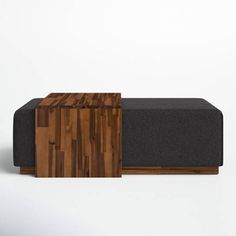 a wooden table sitting on top of a couch next to a black ottoman cover and white wall