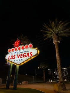 the las vegas sign is lit up at night with palm trees in the foreground