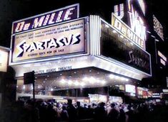 the marquee is lit up at night and people are standing in line to see it