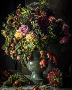 a vase filled with lots of flowers on top of a wooden table covered in leaves