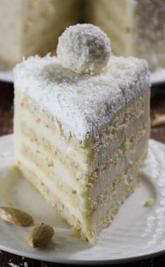 there is a piece of cake with white frosting on the plate and almonds next to it