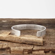 a silver bracelet that says you are my anchor love always sits on top of a piece of wood