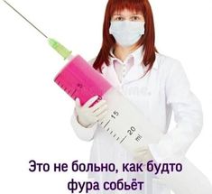 a woman in white lab coat and face mask holding a pink syringe with words on it