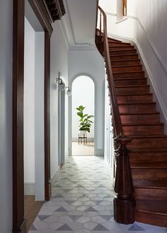 an entry way with stairs and potted plant on the far wall, along with tiled flooring