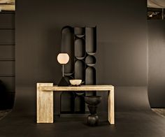 a table with a lamp on it in front of a black wall and some shelves