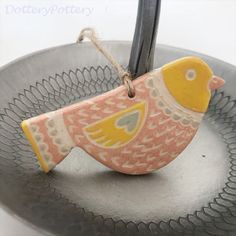 a ceramic bird ornament hanging from a wire on a metal tray with a string