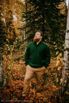 a man with a beard standing in the woods